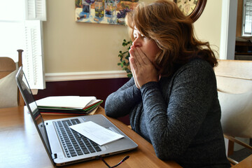 Female using laptop work from home, pay bills, file taxes trying to cope with anxiety worry stress 