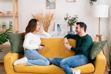 Young couple sitting on sofa and talking to each other