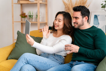 Happy couple sitting on sofa having a video call