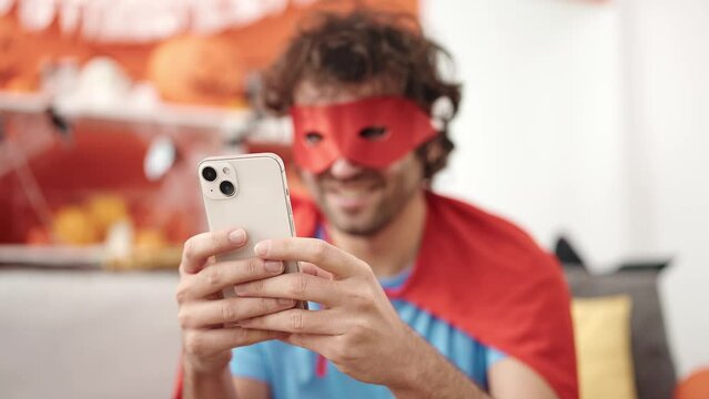 Young hispanic man using smartphone having halloween party at home
