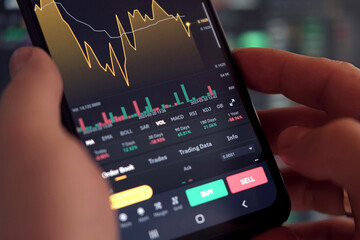 Businessman trader using smartphone checking stock exchange. Man using mobile phone with investing application. Stock market investment and trading cryptocurrency on app in hand. Online business data