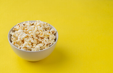 Popcorns in a bowl over yellow background with copy space