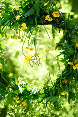 floral wreath with pentagram amulet in forest, green natural abstract background. wiccan magic...