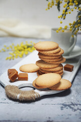 Palets bretons, french cookies. Salted caramel Shortbread Breton cookies, cup of coffee and bouquet of mimosa - 584002021