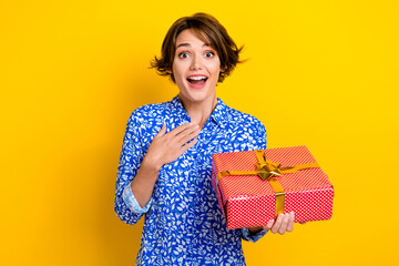 Photo of excited pretty lady wear print shirt getting red gift package isolated yellow color...