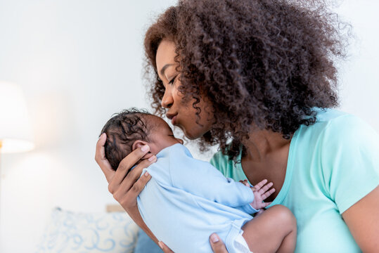 an African American mother kissing forehead his 1-month-old baby newborn son, with happy and love, concept to African American family and baby newborn