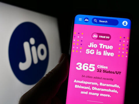 Stuttgart, Germany - 03-18-2023: Person holding smartphone with webpage of Indian telecommunications company Reliance Jio on screen with logo. Focus on center of phone display.