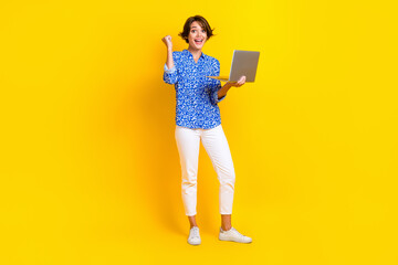 Full size photo of pretty girl raise fist work remotely netbook dressed stylish smart casual clothes isolated on yellow color background
