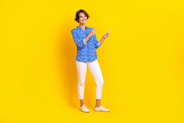 Full length photo of sweet adorable woman dressed blue blouse showing two fingers empty space isolated yellow color background