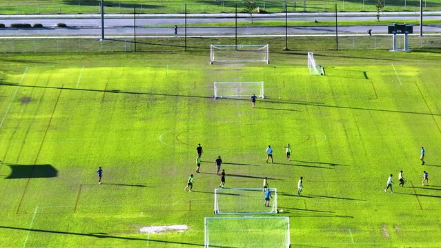 Aerial view of young adult amateur sportsmen playing soccer on grass covered sports stadium. Concept of active lifestyle