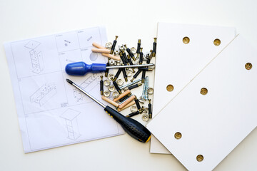 A pile of a various assembly fittings on a white laminated chipboard parts of a new furniture