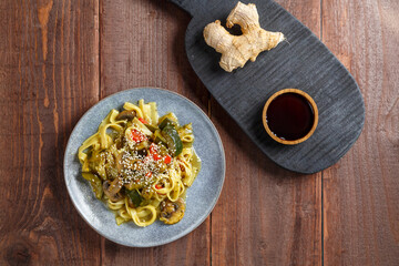 A gray plate with udon vegetables and gibs sprinkled with sesame seeds