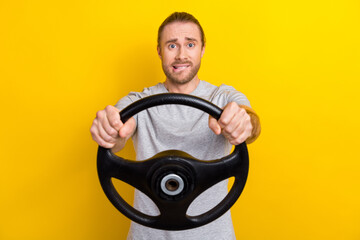 Photo of doubtful unsure man wear grey t-shirt riding car biting lip isolated yellow color...