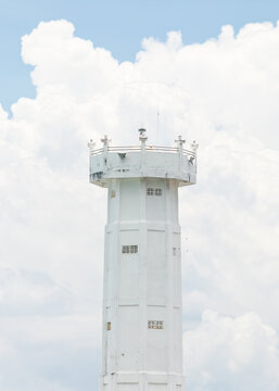 white lighthouse in front of a cloudy bright sky 