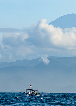 fisher on boat with indonesian flag on water 