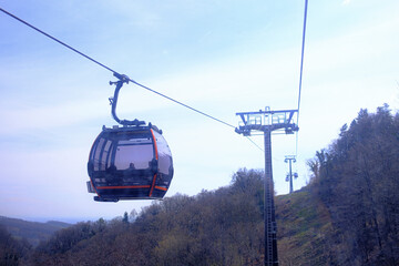 modern cable car on the mountain in motion, early spring, cloudy day