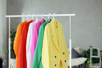Multi-colored bright jackets on a hanger against the background of the room.