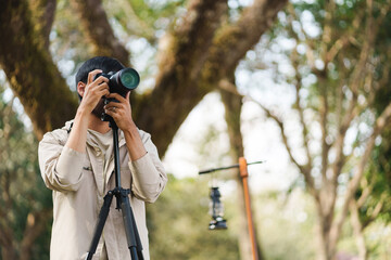 Asian man taking photo by camera enjoying camping outdoors in nature. traveling in the wild