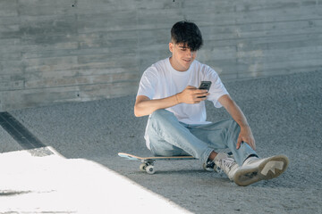 teen boy with skateboard and mobile phone in the street