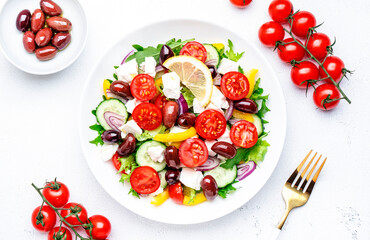 Greek salad with feta cheese, kalamata olives, cherry tomato, yellow paprika, cucumber and onion, healthy mediterranean diet food, low calories eating. White table background, top view