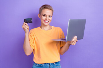 Portrait of pretty cheerful person hold plastic debit card wireless netbook isolated on purple color background