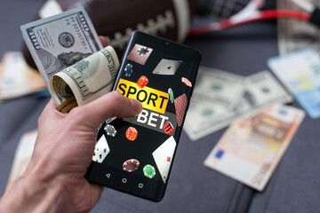 Smartphone with gambling mobile application, ball and money banknotes. Sport and betting concept