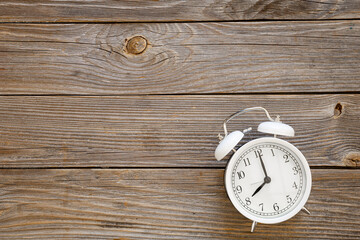 Fototapeta na wymiar White alarm clock on a wooden background, top view, rustic style, copy pace.