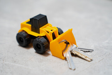 Little toy buldozer pushing big keys and key chain