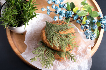round cookies with milk and sprigs of rosemary and thuja. Blue blueberries and blueberries on a black background