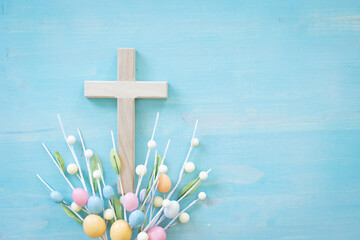 Wood cross with easter egg decorations on a blue wood background with copy space