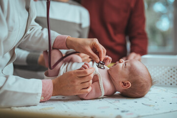 Doctor examining small kid with stethoscope in clinic. Doctor listening small childs lungs with stethoscope. Close up of pediatrician hand using a stethoscope to listen and checking heartbeat.