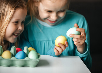 Fototapeta na wymiar Two small cute girls with amazing smile playing in a game with eggs, beat eggs in a fight