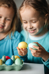 Fototapeta na wymiar Two small cute girls with amazing smile playing in a game with eggs, beat eggs in a fight
