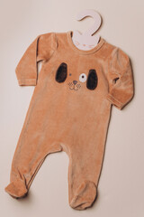 Baby boy newborn bodysuit with cute dog face on beige background. Children's clothes. Flat lay. Top view. Copy space. Fashion outfit