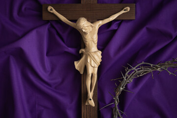 Crucifix with crown of thorns on a dark purple fabric background