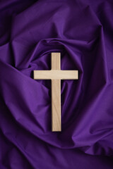 Wood cross on a dark purple fabric background
