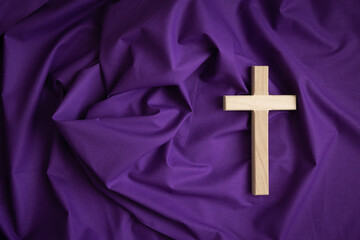 Wood cross on a dark purple fabric background