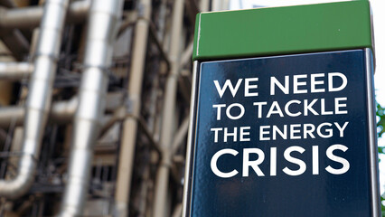 We need to tackle the energy crisis on a sign in front of an Industrial building	
