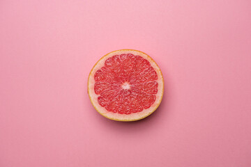 Juicy organic grapefruit cut in half on a pink background. Cool minimal flat lay, copy space. Healty breakfast or diet concept.