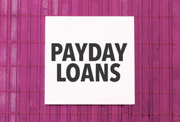 white sticker with text payday loans on pink wooden background