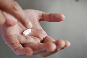 Close up of man hand holding pills with copy space  - obrazy, fototapety, plakaty