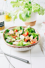 Healhty tuna salad with tomato, quail eggs, lettuce and salad dressing with olive oil, lemon juice and grain mustard.