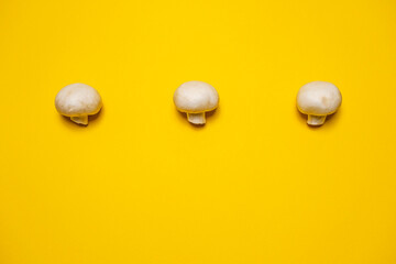 Fresh whole champignon mushrooms on a yellow background. Cool minimal flat lay, copy space.