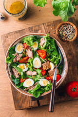 Salad with canned tuna, tomato, quail eggs, lettuce and salad dressing with olive oil, lemon juice and grain mustard.