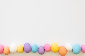 Border of colourful Easter eggs in a row on a white background with copy space