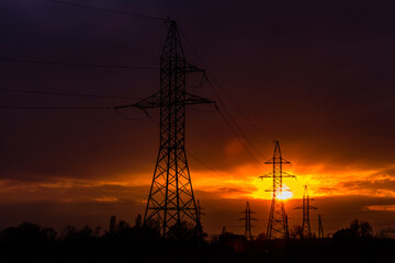 High voltage power line at sunset. Silhouettes of the metal pillars