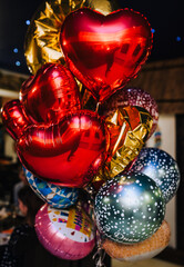 Background of beautiful multi-colored balloons, red in the form of a heart from foil. Photography, holiday, copy space, valentine's day. The text "happy birthday" is written in Ukrainian.