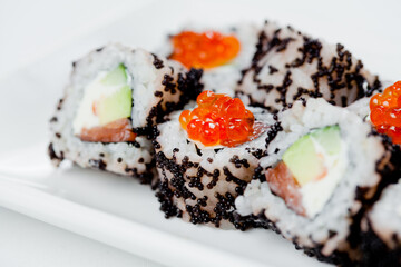 Japanese sushi with salmon, Philadelphia cheese, avocado in white rice and flying fish roe with salmon caviar