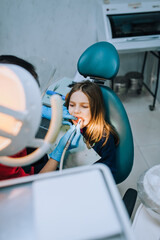 Dentist, doctor in rubber gloves with tools diagnoses, treats teeth from caries of a girl, a child...