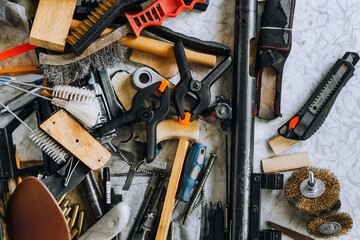 A pile, a lot of household tools are scattered randomly on the table in the mechanic's workshop. Close-up photo, household junk, top view. The concept of locksmith work.